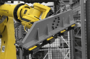 Yellow industrial arm with a magnetic gripper holding a steel plate
