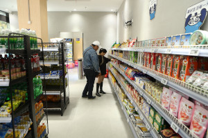 Shoppers beside stocked grocery shelves